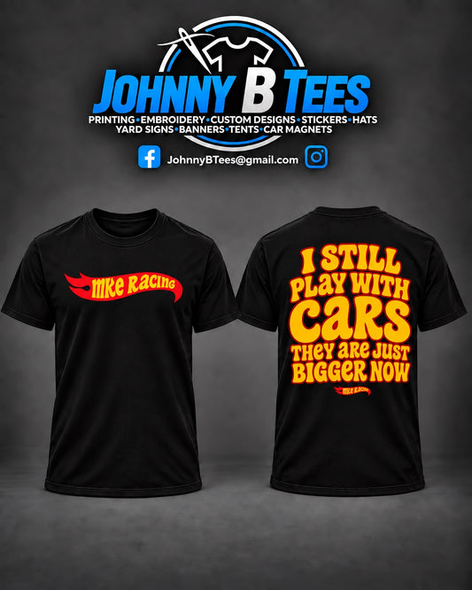Front and back of a black MKE Racing T-shirt with red and yellow graphics and the words I still play with cars, they are just bigger now.